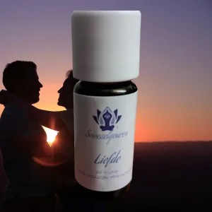 Een flesje etherische olie met op het etiket snoezelgeuren liefde met op de achtergrond een omarmend koppel bij zonsondergang.